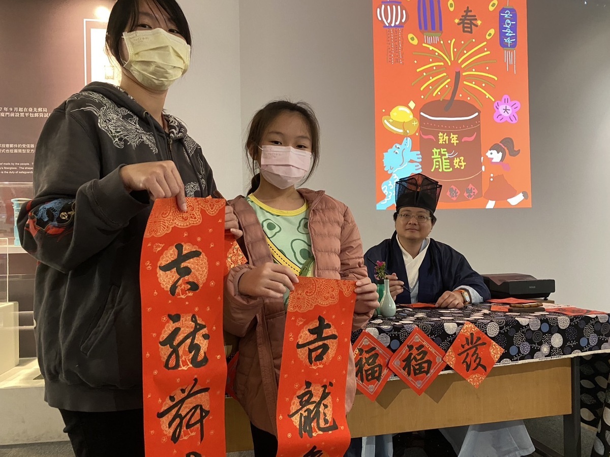 藍仕豪(右)揮毫教寫春節斗方。 圖：郵政博物館高雄館/提供