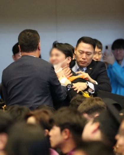 該名畢業生在被摀嘴後，隨即遭到警衛人員強行架出場。 圖：翻攝自 @0926kgj X帳號