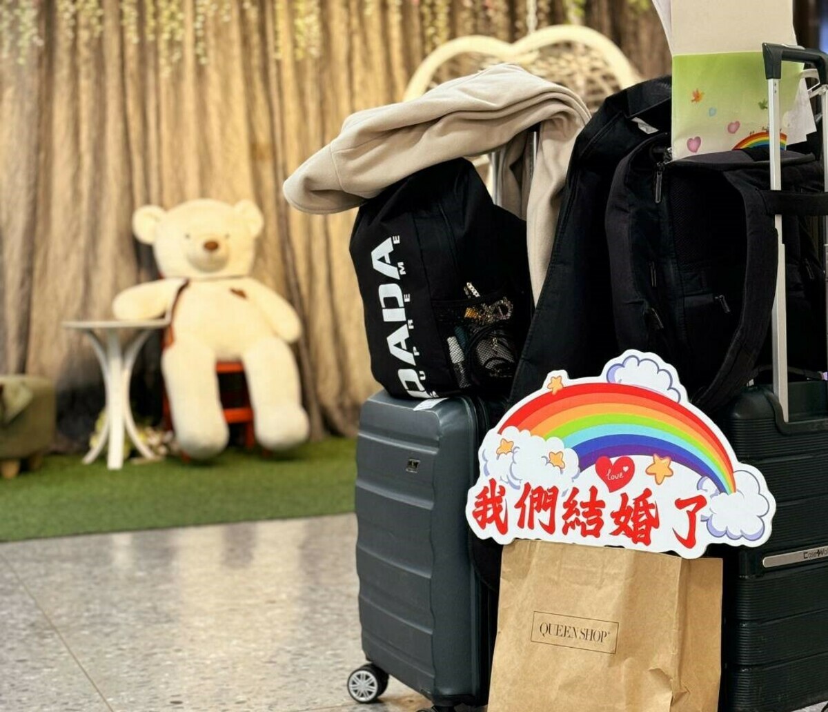 兩人拉著行李辦理結婚登記。 圖：高雄市民政局/提供