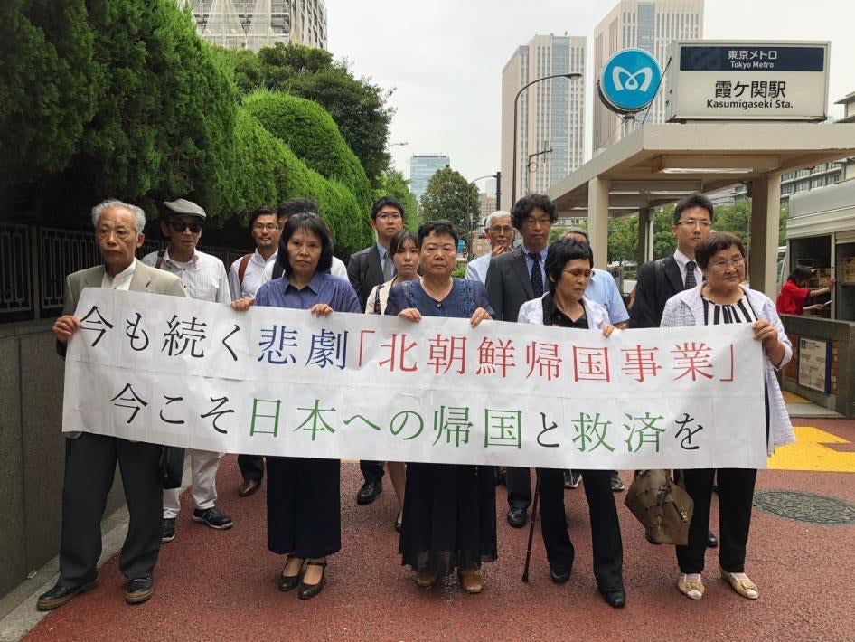 曾跟隨北韓歸國運動抵達北韓，而後棄朝脫北的5名脫北者，在2018年於日本法院對北韓提起訴訟。5名原告在支持者的陪同下拉起布條，上頭文字意為「現在仍在持續的悲劇『北韓歸國運動』，現在正是時候給他們救贖讓他們回日本」。在日朝鮮人大多是在二戰時期到日本工作，或是在韓戰偷渡來到日本的。 圖／Human Rights Watch
