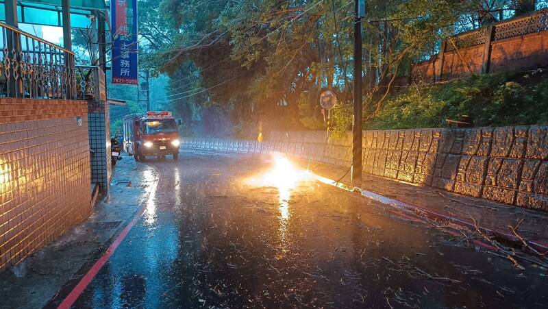 受到強風、強降雨影響，新北市淡水區新民街31日下午發生電纜線斷裂垂落、冒出火花等災情，警消到場管制。 圖：中央社/翻攝畫面