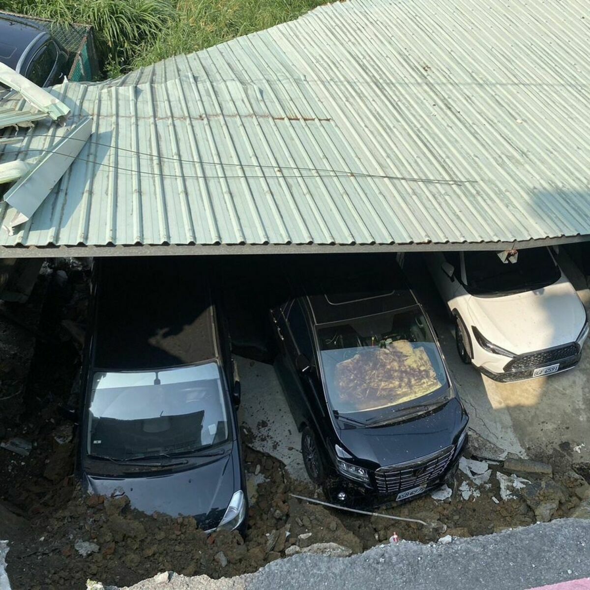 花蓮發生 403 大地震，新北市新店區安泰路土坡滑落、地面龜裂，居民搭建的停車設施遭到土石掩埋受困，一度傳出新北市停班停課的消息，但遭到網紅四叉貓查證為錯誤資訊。 圖：新北市消防局提供