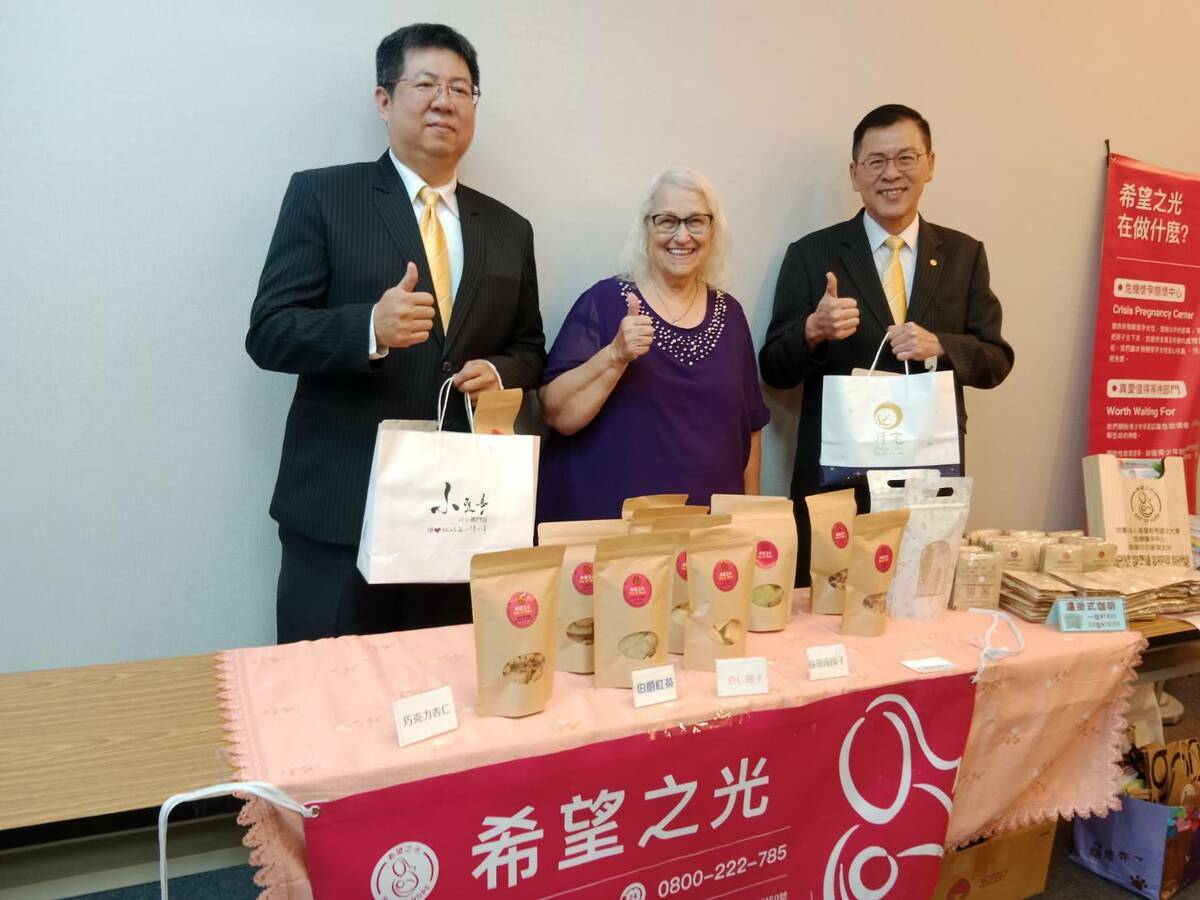 洪伍賢(右)在義賣攤位採購愛心餅乾。 圖：孫家銘攝
