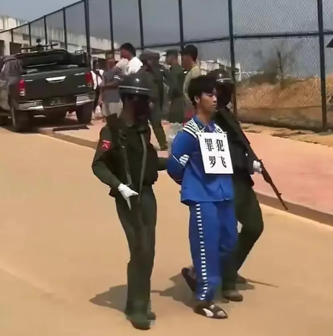 這些犯罪嫌疑人穿著藍色囚服，手腳帶著手銬和腳鐐，脖子上掛著寫有姓名的牌子，由兩名同盟軍士兵押送。 圖 : 翻攝自網易