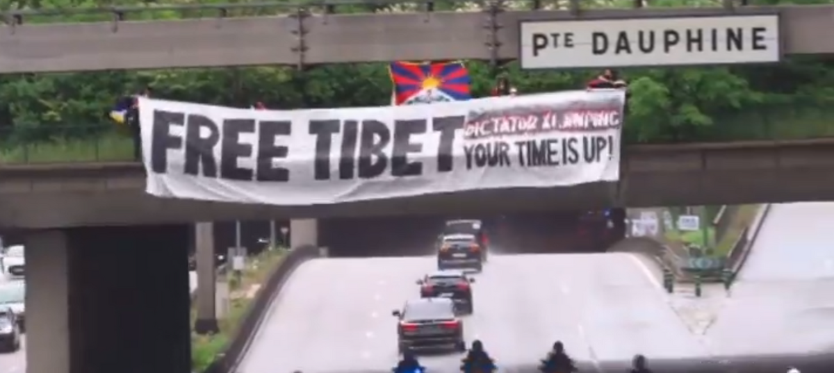 藏人在習近平車隊會路過的地方，舉起抗議中國的標語。 圖：翻攝自 STUDENT FOR A FREE TIBET