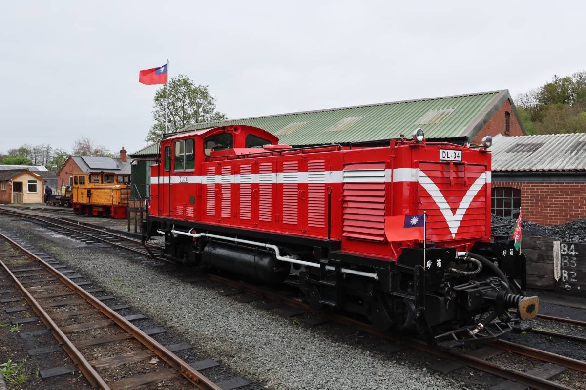 DL-34柴油機關車經典紅色火車頭搭載著國旗，迎風在當地無垠的秀麗綠野飄揚。 圖：林業及自然保育署／提供