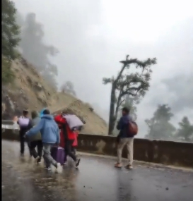 雲南省的獨龍江公路在當地時間 2 日因降雨導致發生山體滑坡事故，受困的遊客棄車拉行李走在馬路上。 圖 : 翻攝自騰訊網