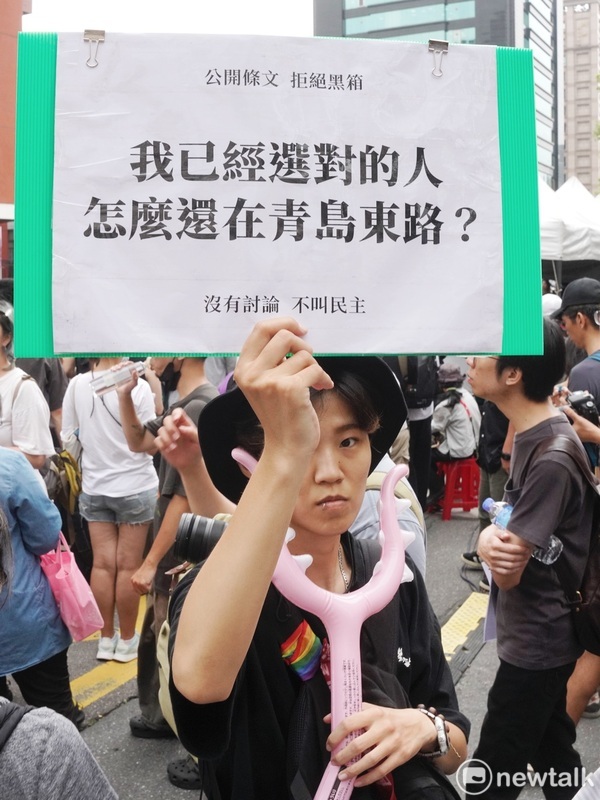 一位女性民眾舉牌表達對藍白兩黨強行通過國會擴權法案的不滿。 圖：張良一/攝