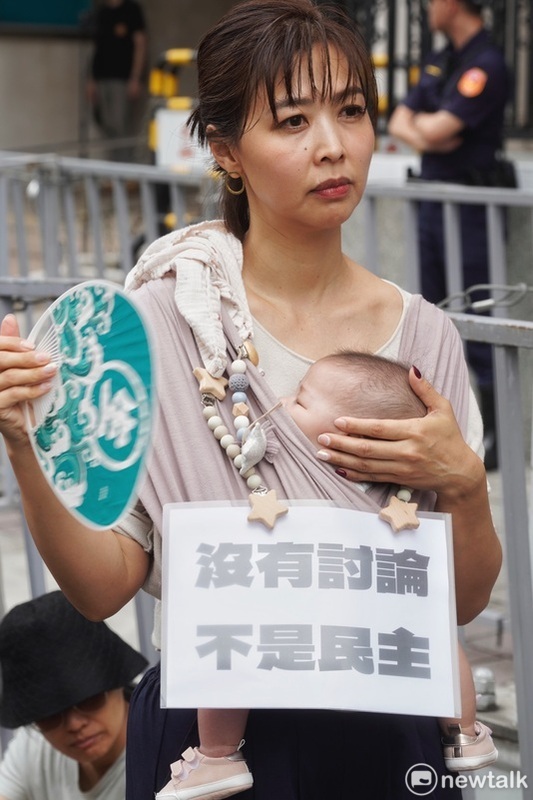 一位年輕媽媽揹著稚兒參與抗議藍白兩黨強行通過國會擴權法案。 圖：張良一/攝