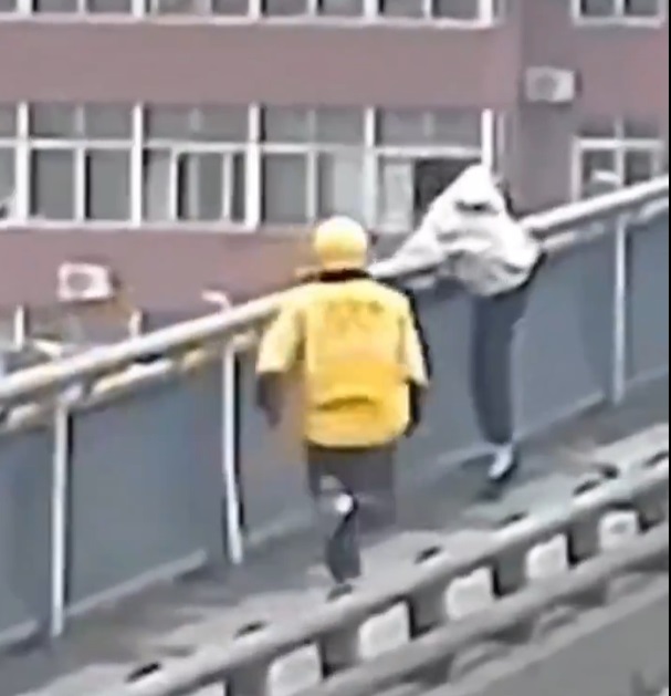 母親將嬰兒放在一旁後準備跳橋，一位開車經過的外賣員迅速棄車並攔阻她。 圖：翻攝自 Feiyan Xie X（前推特）帳號