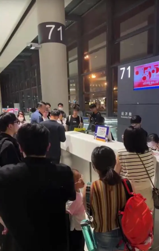 多名旅客圍在機場內一個櫃台前，和工作人員進行交涉。 圖：翻攝自極目新聞
