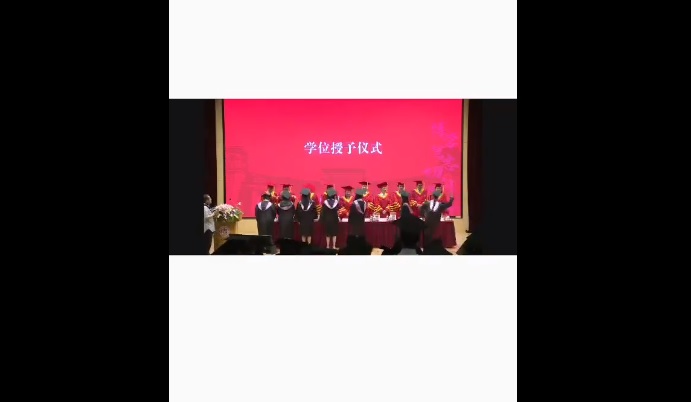 復旦大學法學院昨日( 19 日)舉辦畢業典禮，但一名畢業學生在典禮上直接朝授予證書的老師呼了一巴掌。 圖：擷取自 @xinwendiaocha X 分享影片