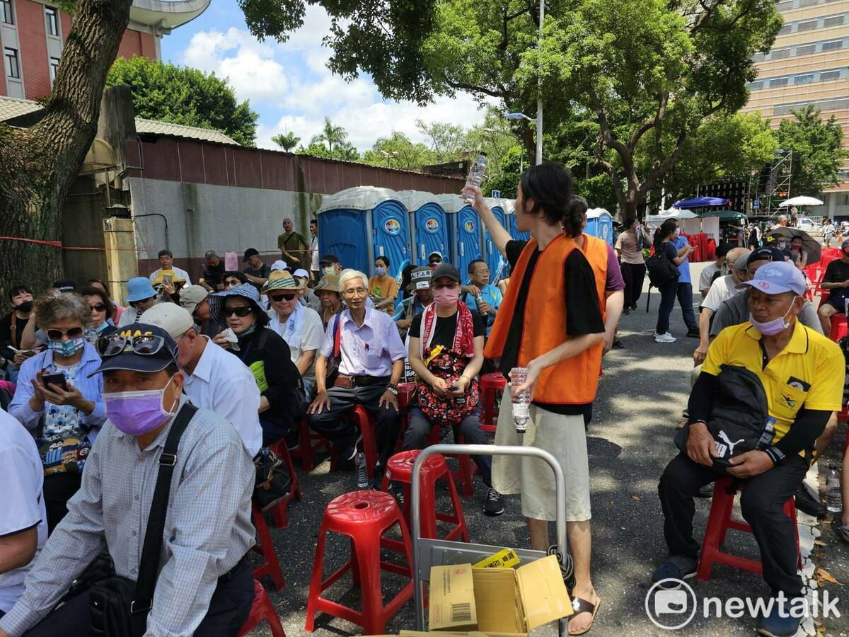 主辦單位工作人員發放飲水，提醒民眾注意高溫、隨時補充水分。 圖：林昀真/攝