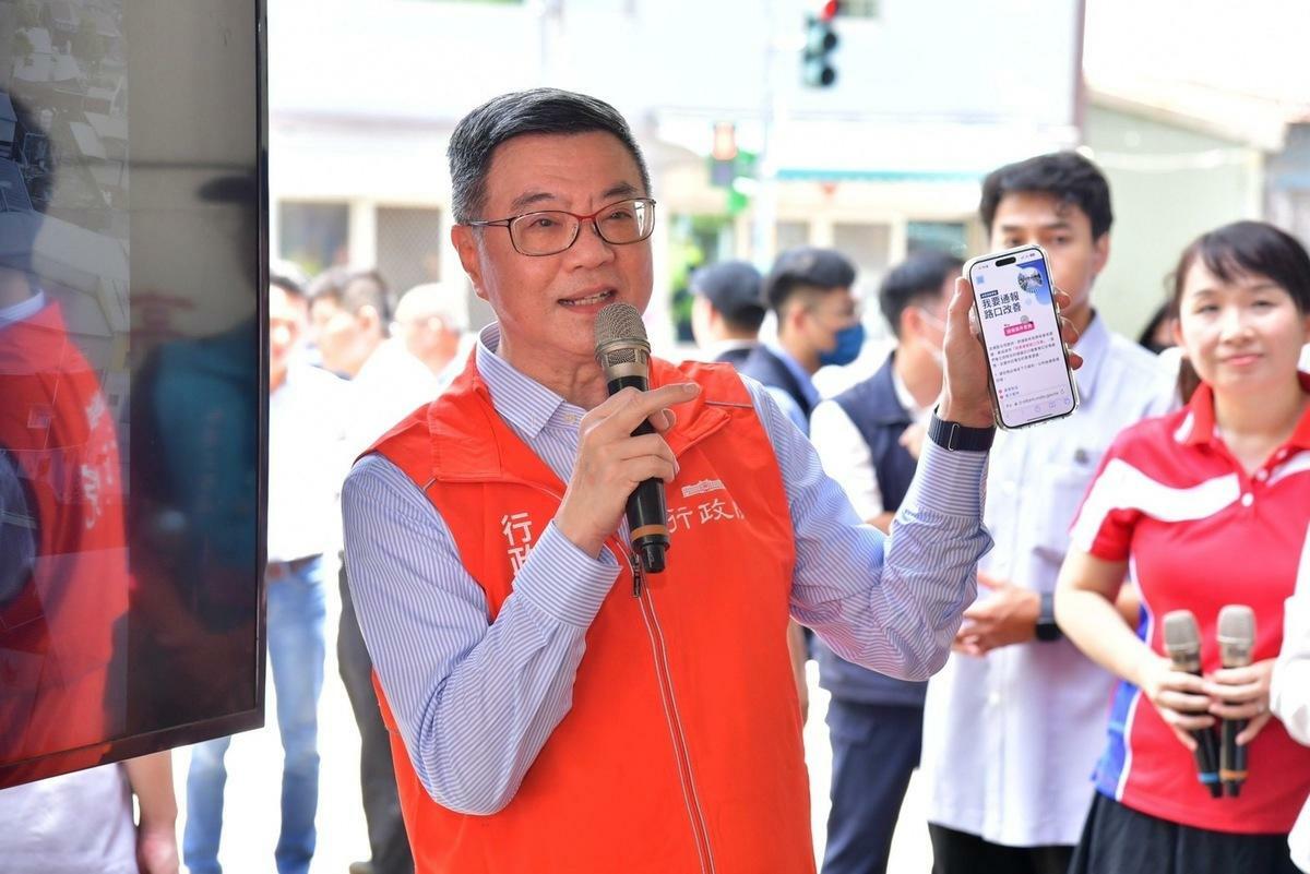 卓榮泰視察「永續提升人行安全計畫改善成果」，並以手機展示「道安總動員」平台服務資訊。 圖：行政院提供