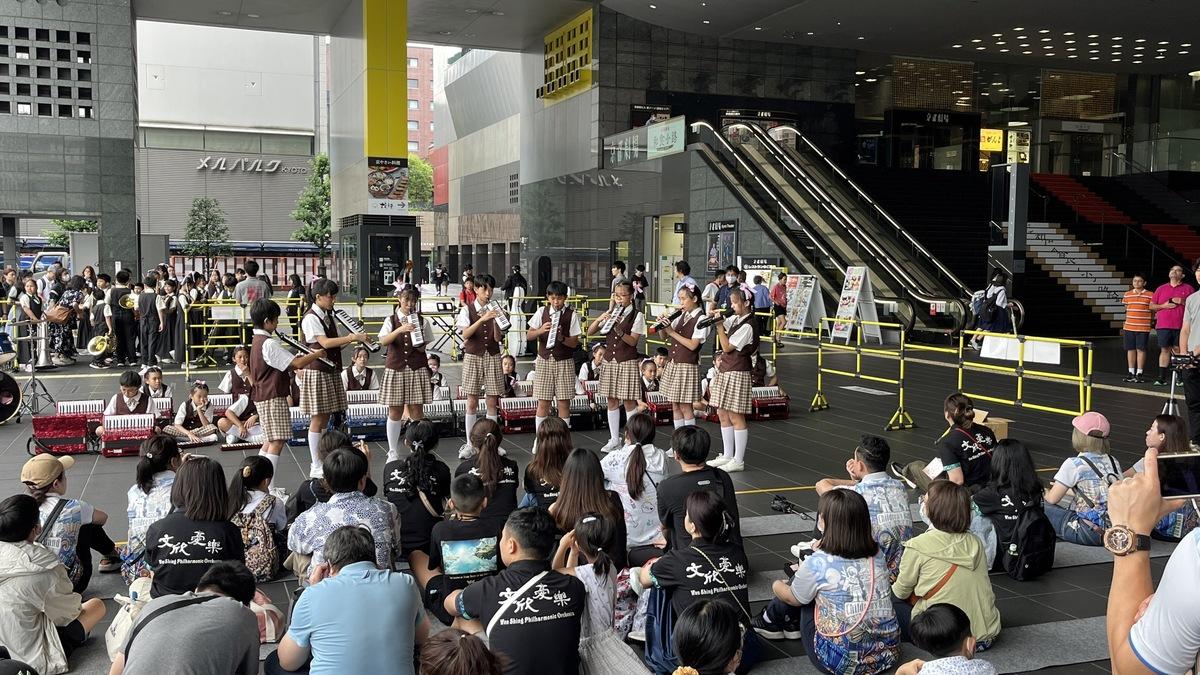 桃園市大竹及文欣國小樂團學員在京都JR車站進行快閃演出，吸引來往旅客駐足欣賞。 圖：吳俊生/提供