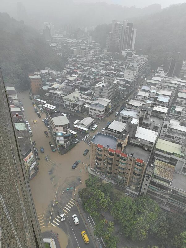 台北市吳興街公車總站的交叉路口則是可見黃泥水淹沒道路，不少車輛涉水通行或來不及挪移浸在突發的大水中。 圖：翻攝「臉書」信義區三兩事社團/邱詩喬