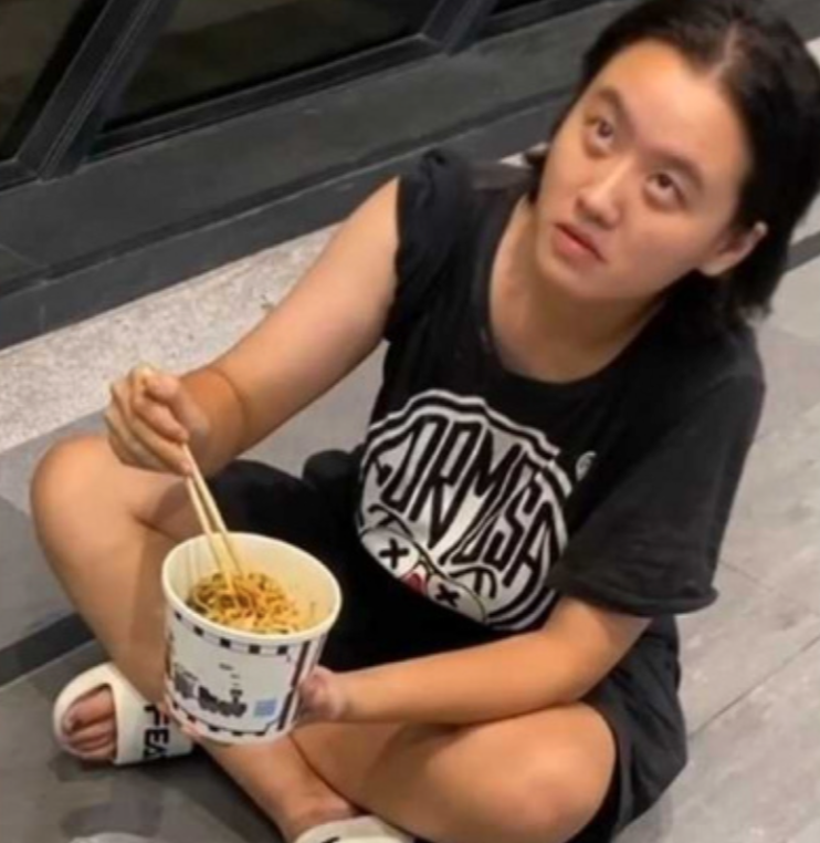 林靖恩闖入大樓偷拿他人訂購的外送餐點，直接坐在路邊地上吃起食物，警方依竊盜罪將林靖恩帶回偵辦。 圖：翻攝自Threads