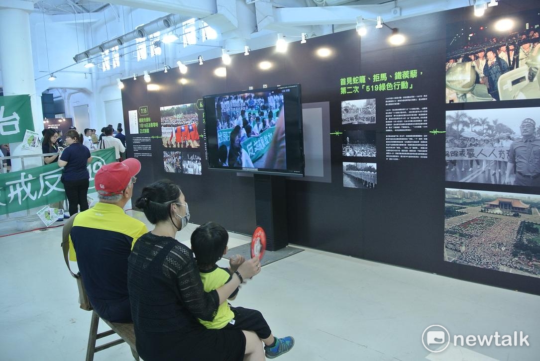 民眾坐在長板凳上看解嚴30影像展的影片，有復古味道。 圖：唐復年/攝
