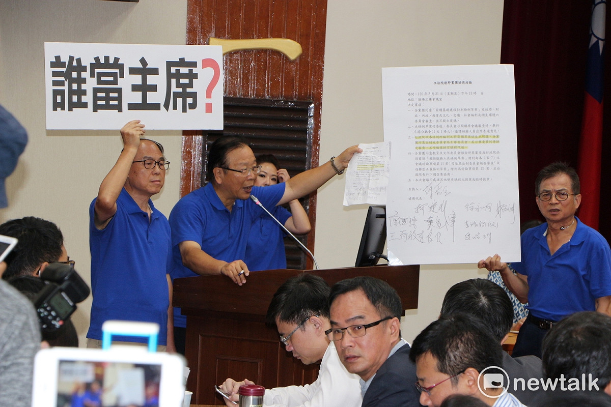 國民黨立委們於黨團大會後高舉「誰是主席？」牌子走進會場，黨團總召林德福質疑「誰是主席？」應經協商。 圖：廖品瑄／攝