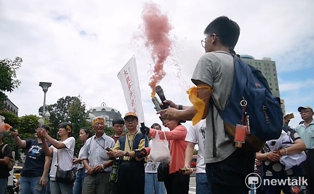 居民朝行政院內投擲煙霧，象徵大觀社區居民如生活在迷霧之中，沒有方向與未來。 圖：鍾孟軒/攝