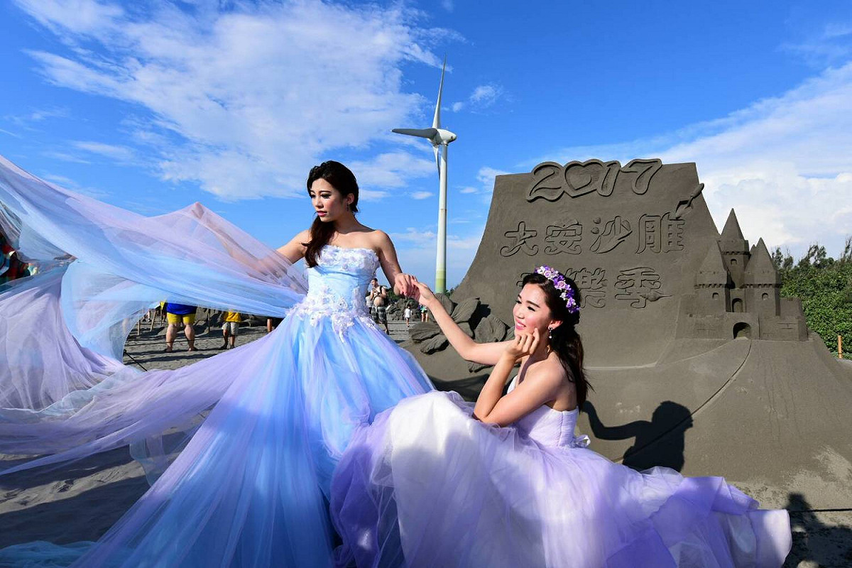 沙雕前面有人婚紗？其實是「大安沙雕音樂季」的攝影大賽，昨(16)日舉辦攝影比賽，主辦單位找來3名模特兒穿著婚紗，讓民眾拍攝婚紗作品，參加比賽。 圖：台中市觀光旅遊局提供