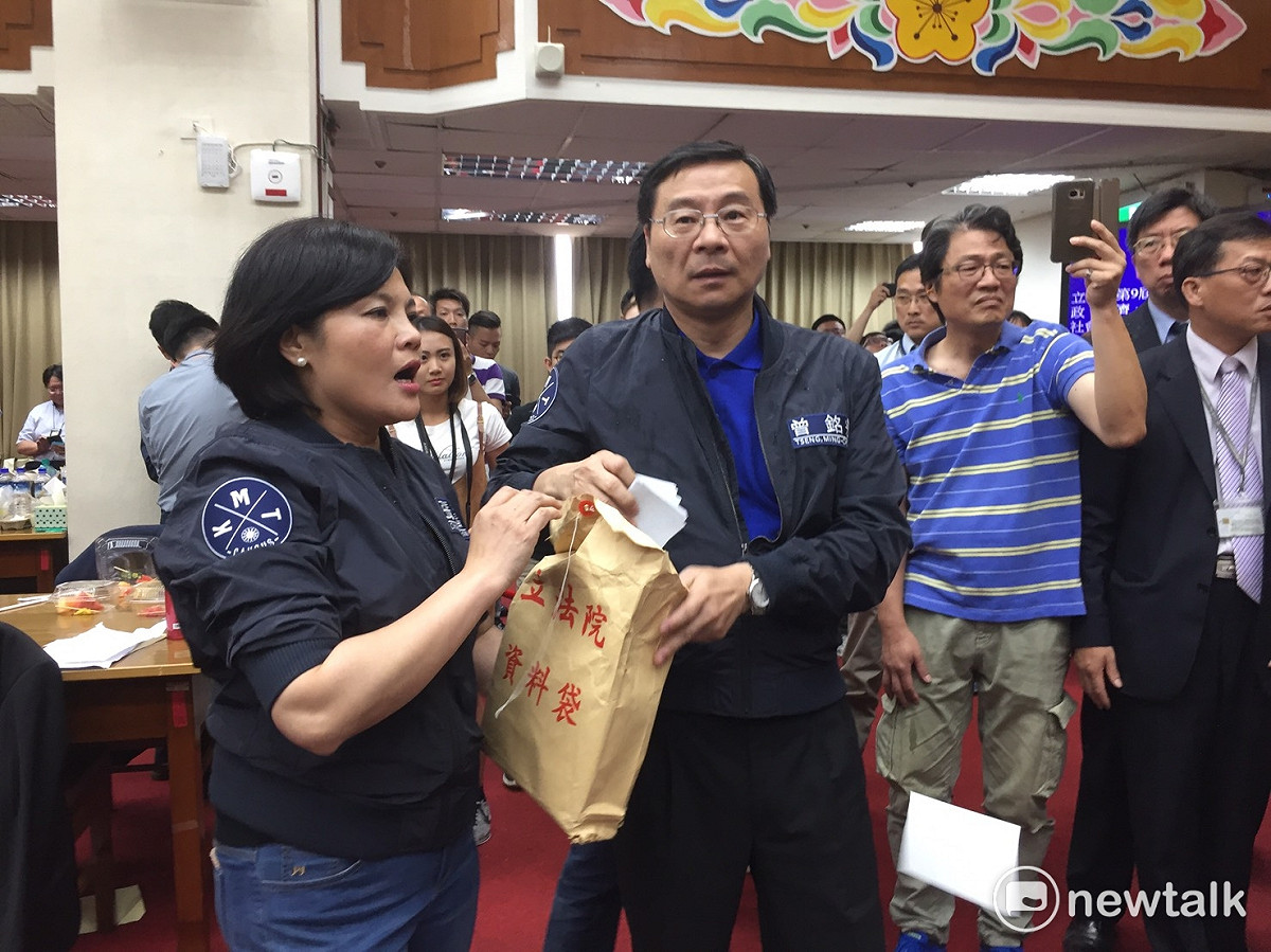 詢答結束後，國民黨團不滿王榮璋繼續指示議事人員宣讀提案，祭出灑紙鈔、丟水球，朝主席台方向丟去。 圖：廖品瑄/攝