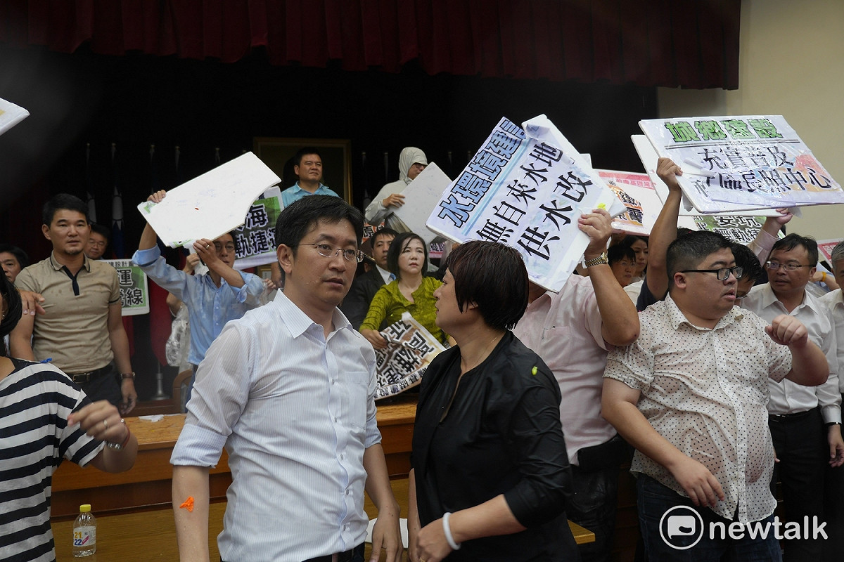 面對國民黨水球攻勢，綠委紛紛拿起看板或用手遮雨，但仍不敵雨勢，全身濕透。 圖：廖品瑄／攝