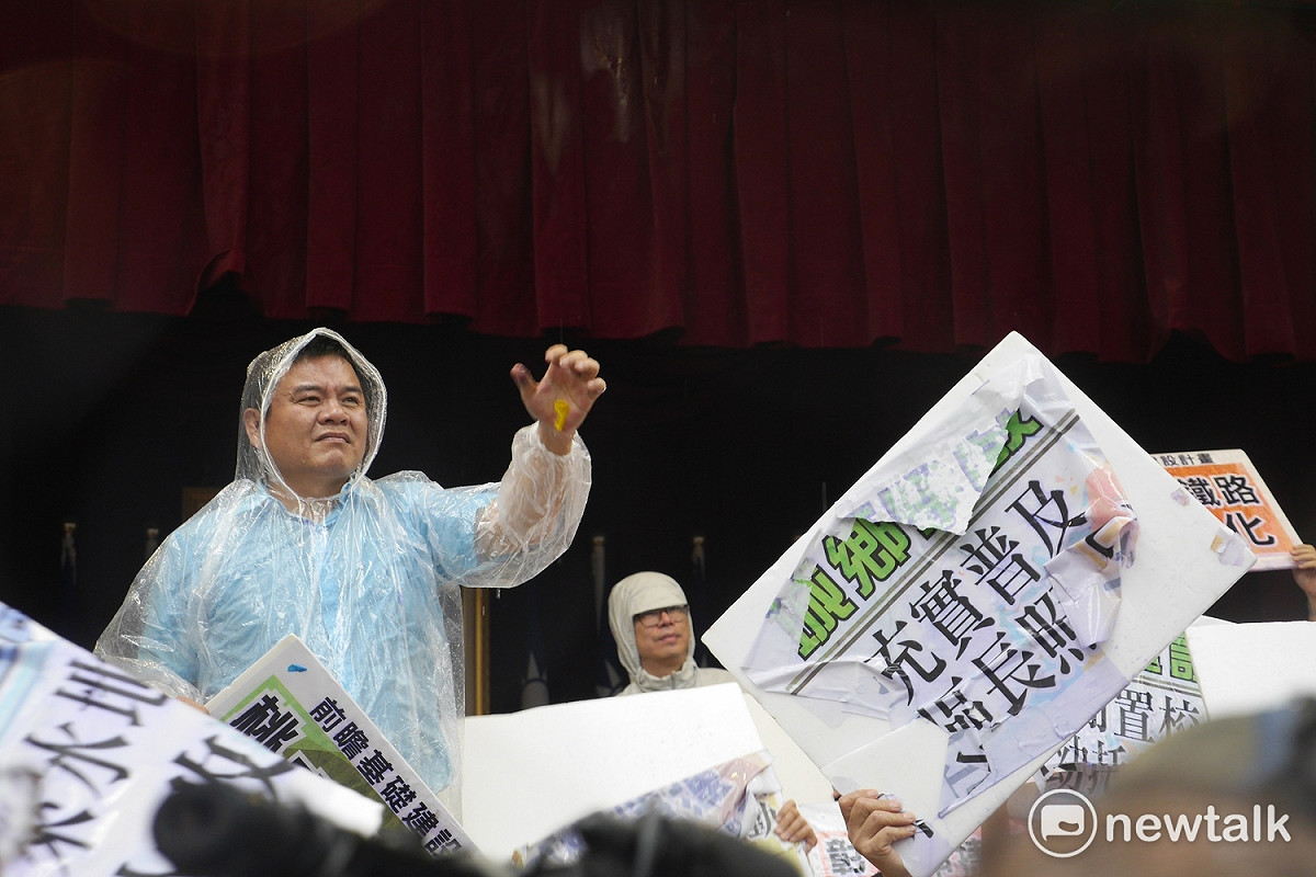 綠委皆護衛在主席台上，綠委莊瑞雄穿起雨衣抵擋水球。 圖：廖品瑄／攝