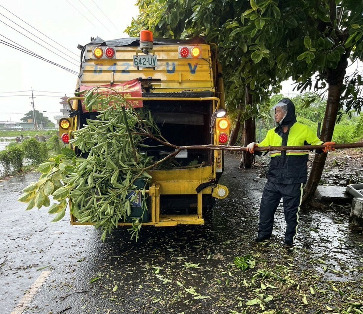 清潔隊人員冒風雨清理路上斷落的樹枝，保障行車安全。 圖：高雄市環保局/提供