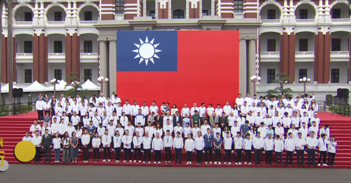 總統賴清德與副總統蕭美琴與我國奧運代表團在巨幅國旗前合照。 圖：截自賴清德YT