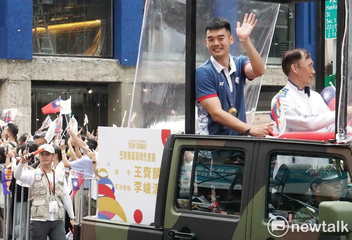 巴黎奧運羽球雙打金牌選手王齊麟站在吉普車上向民眾揮手致意。 圖：張良一/攝