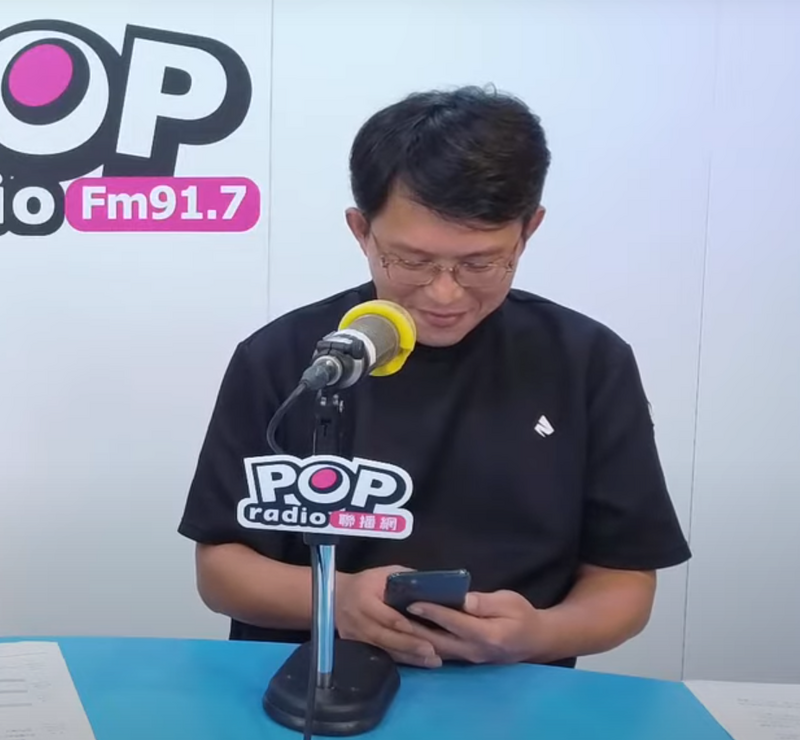 黃國昌接受廣播節目訪問時，得知柯文哲被裁定收押後，一瞬間露出一抹微笑被抓包。 圖：翻攝POP Radio聯播網YouTube