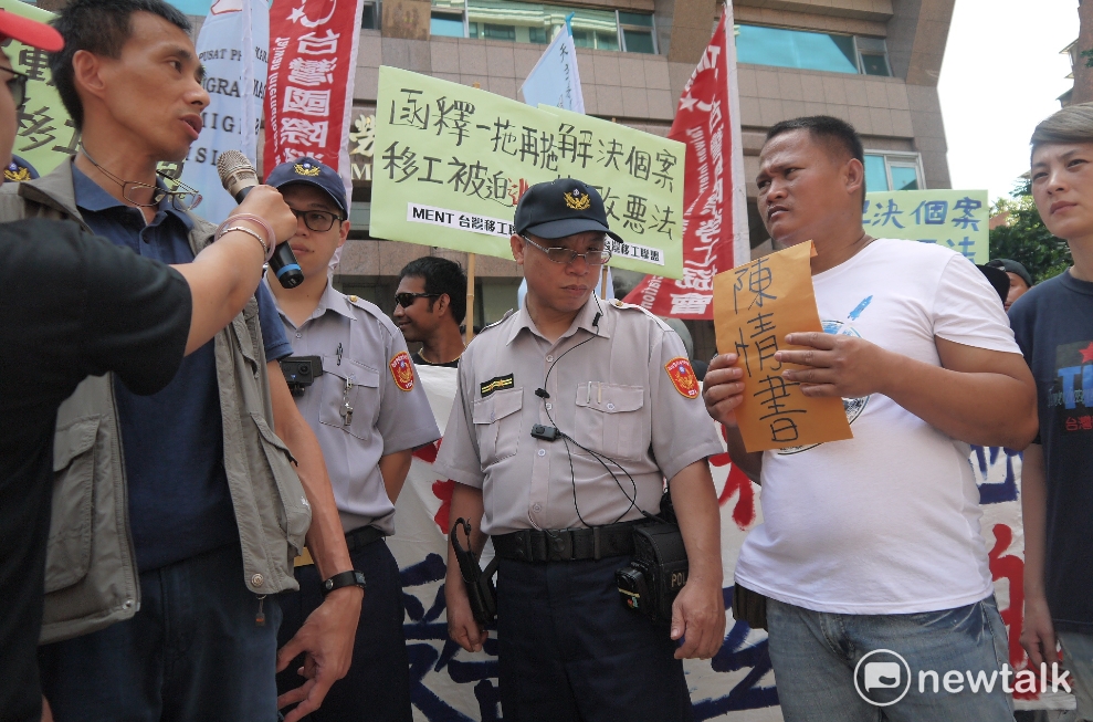 勞動部官員與漁工J先生。J先生正要把陳情書交給勞動部官員，希望勞動部能盡快解決撤銷逃跑移工的註記，否則一年多來完全沒收入也無法工作。 圖：鍾孟軒/攝