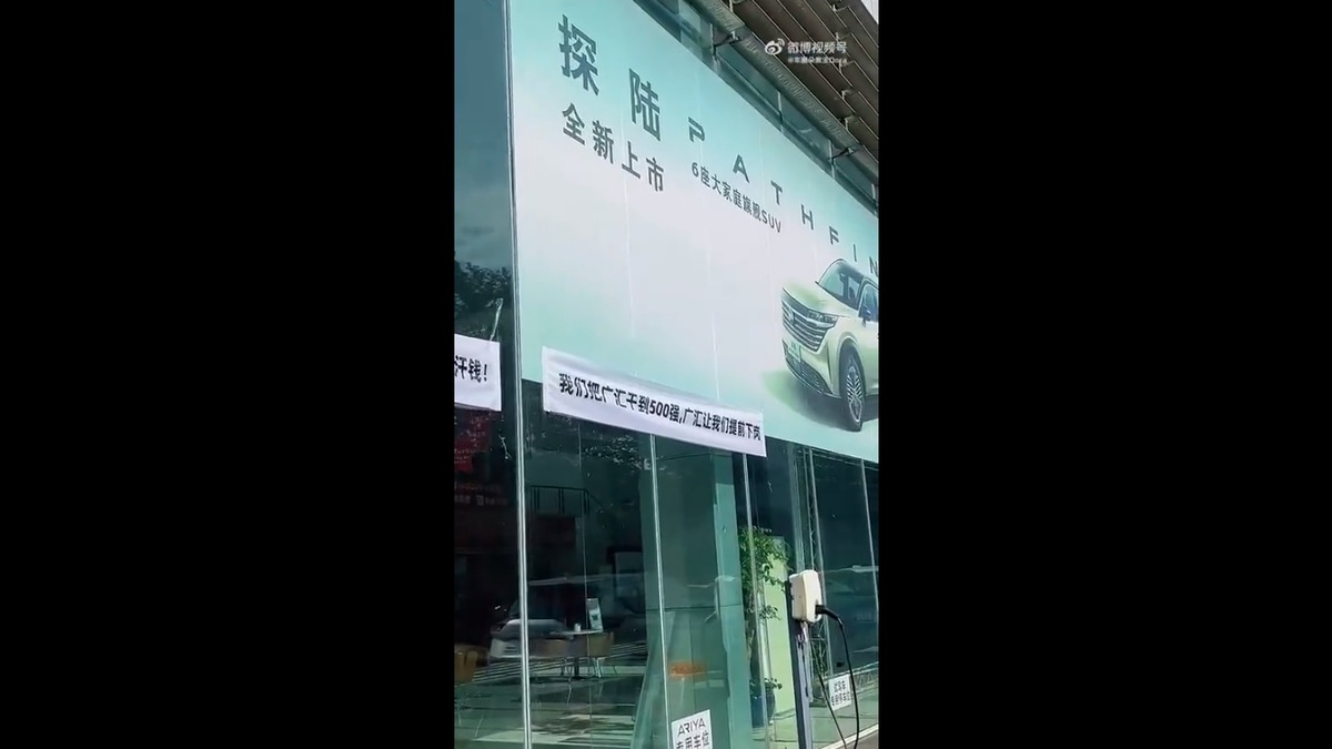 在四川省成都市廣匯日產申科蓉 4S 店的員工因不滿突遭解聘，選擇前往店面掛橫幅標語抗議維權。 圖：擷取自 @whyyoutouzhele X 分享影片