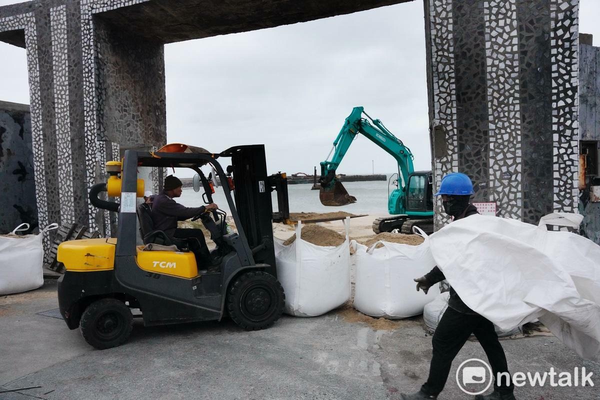 東莒猛澳港工作人員將沙包堆在沙灘出入口，以避免颱風捲起的大浪沖進民宅內。 圖：張良ㄧ/攝