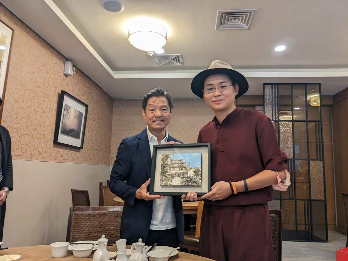 台南年輕畫家邱郁仁也贈送畫作給菊池市代表團，此畫是由特殊方式以茶調入墨色，因此散發出淡雅茶韻。構圖則是以迎春門（東門城）為主體，重現往日熙來攘往的人潮，用以象徵雙方的情誼往來與互動頻繁。 圖：黃博郎／攝