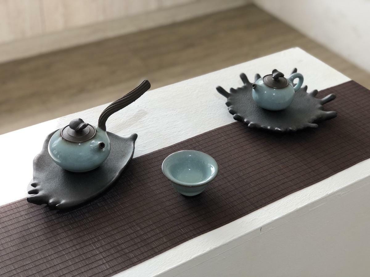「墨韻行書」系列作品以青瓷茶具展現行書中的點、撇、橫和豎等筆法，並以天目無光黑釉茶盤襯色，帶出茶具與書法之雅致，巧妙結合書法、青瓷和茶器的特色。 圖：黃博郎／攝