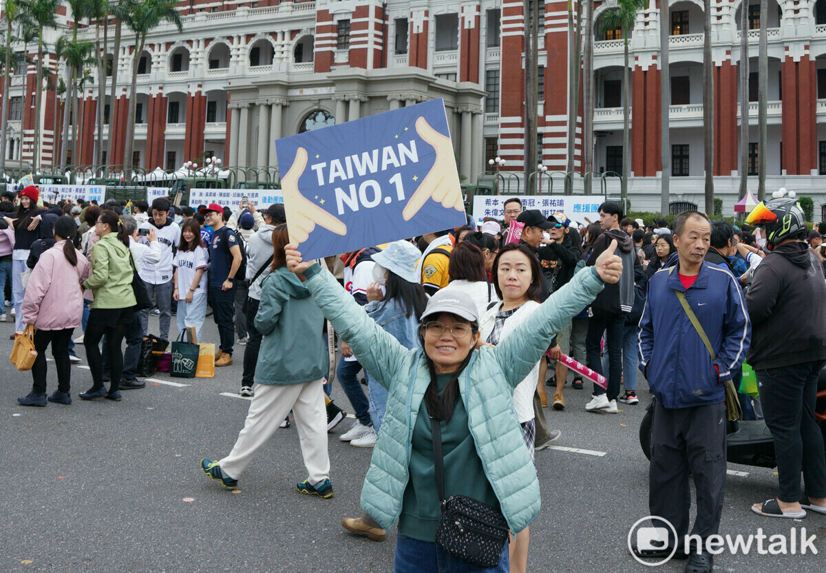 熱情的民眾們跟著台灣英雄走到總統府前，並拿著自製海報拍下值得紀念的一刻。 圖：張良一/攝