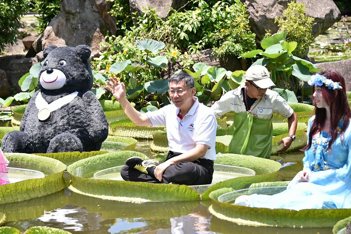 柯文哲帶上台北世大運的吉祥物熊讚一同坐上大王蓮，他在入｢座｣前表示有點毛毛的，所幸柯最後穩坐大王蓮，沒有落水。 圖：台北市政府／提供