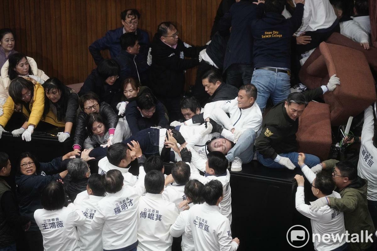 國民黨立委廖先翔（圖中臥倒者）衝入眾民進黨立委間，被多人壓至放倒在桌上後，國民黨立委趕來幫忙，隨後廖先翔為趕走壓在身上的林淑芬，以剪刀腳也弄倒對方，林淑芬則靠著范雲解救才脫困。 圖：張良一/攝