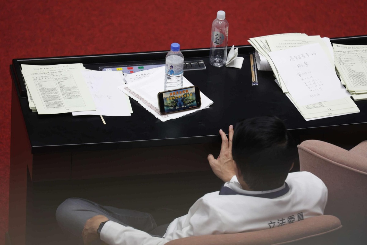 立院主席台衝突之際，謝龍介在台下翹腳看著題為「如果發生武統，台灣民眾會不會反抗」的影片。 圖：翻攝周軒臉書