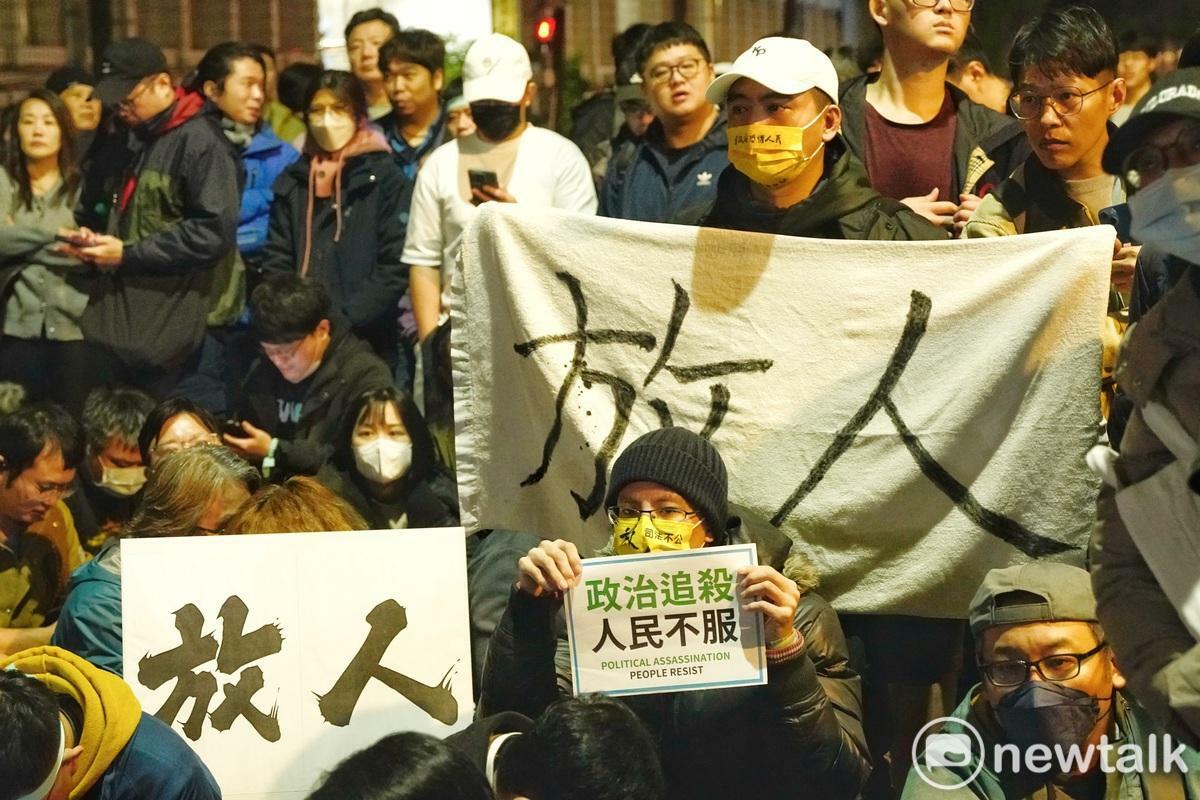 一位民眾黨的支持者在台北地檢署外舉著「放人」、「政治追殺 人民不服」的布條和牌子聲援正在北院接押庭應訊的民眾黨主席柯文哲。 圖：張良一/攝(資料照)