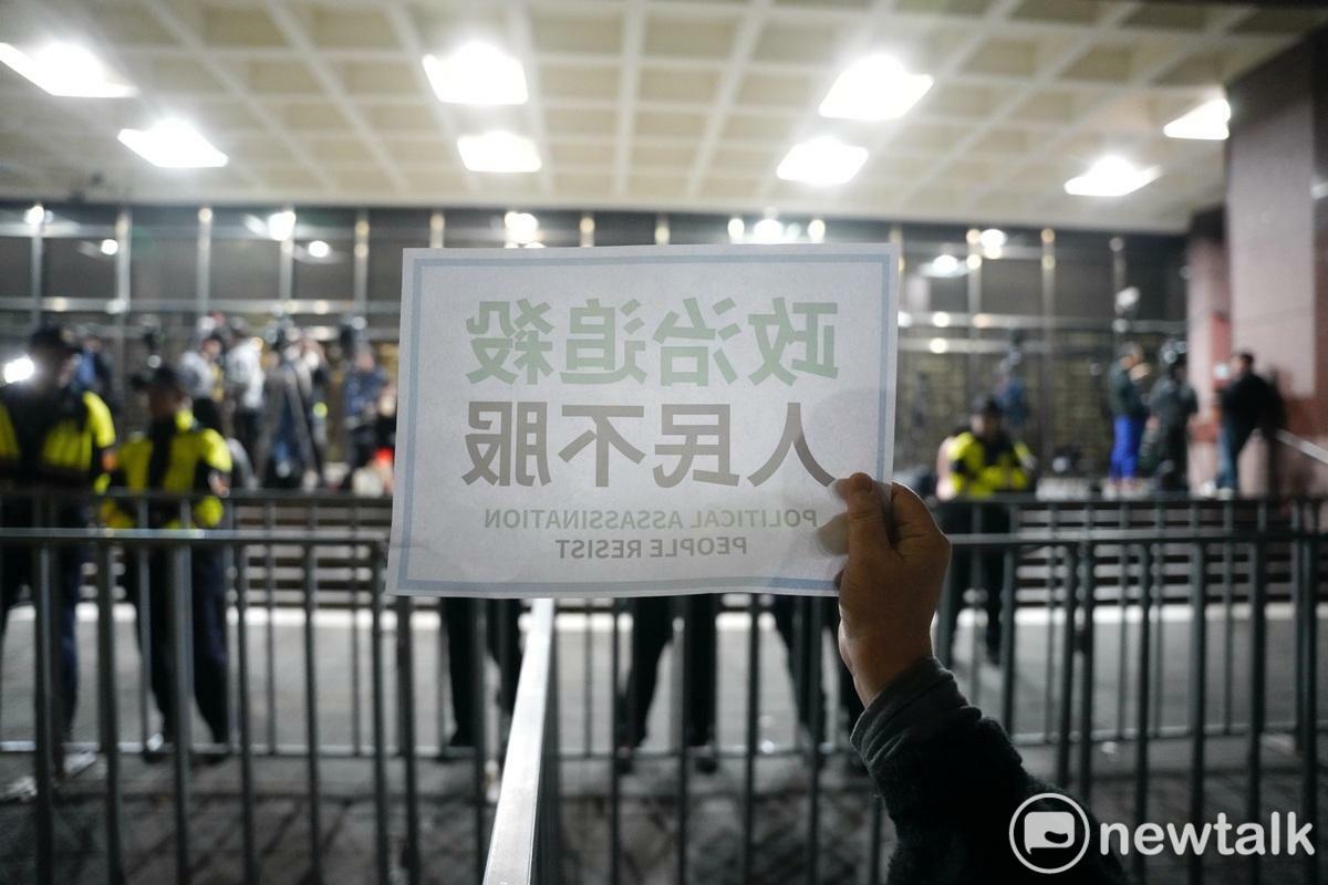 一位民眾黨的支持者在台北地檢署外舉著「政治追殺 人民不服」牌子聲援民眾黨主席柯文哲。 圖：張良一/攝