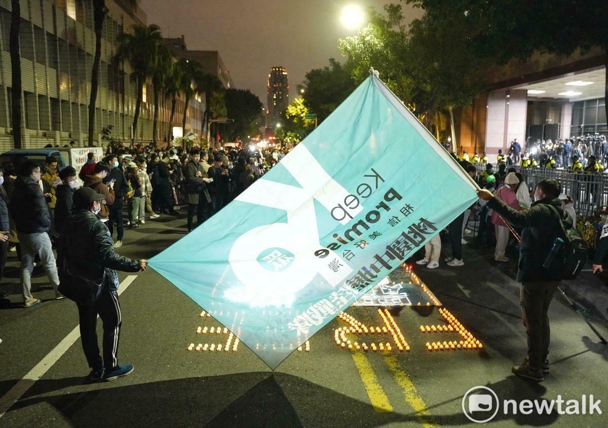 兩位民眾黨支持者舉著柯文哲競選總統旗幟，向守候在北檢外的支持者加油打氣。 圖：張良一/攝