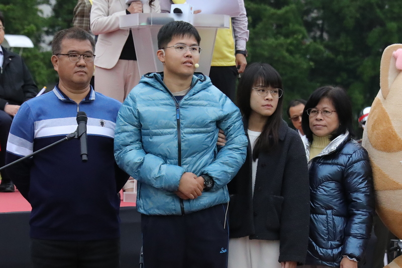 傘兵秦良丰（左2）下士民國107年跳傘墜地重傷，奇蹟存活，他獲邀擔任「高雄市各界慶祝中華民國114年元旦升旗典禮」國歌領唱，1日由家人陪同站上舞台。 圖/中央社