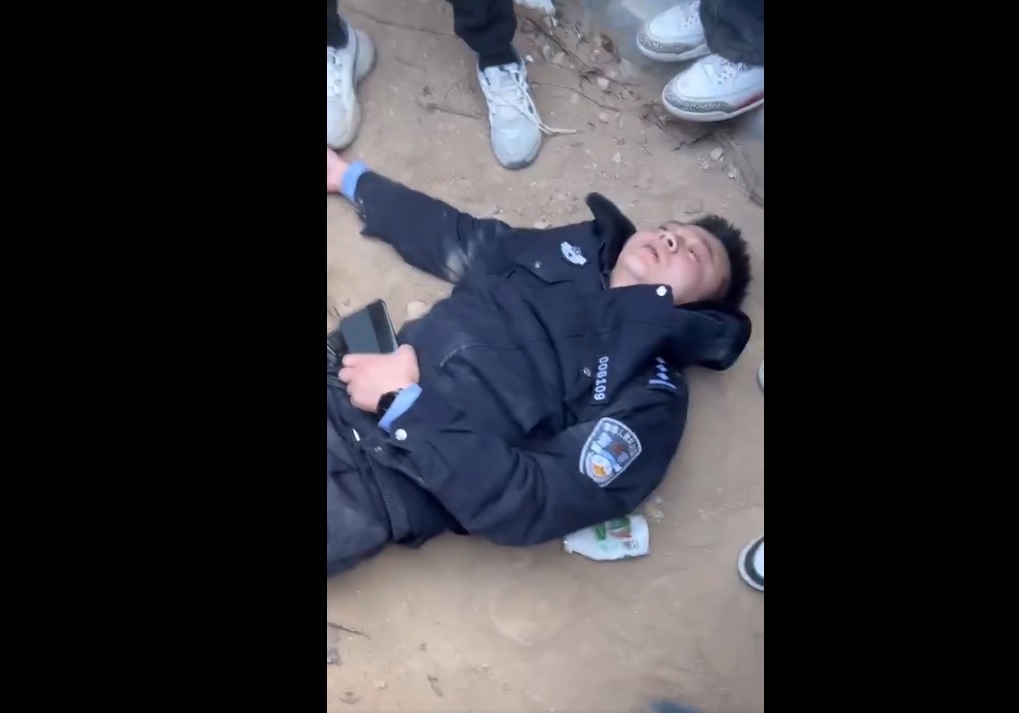 有警察在被民眾打倒後，躺在地上裝死，但左手卻緊緊抓著自己的手機。 圖：擷取自 @YesterdayBigcat X 分享影片