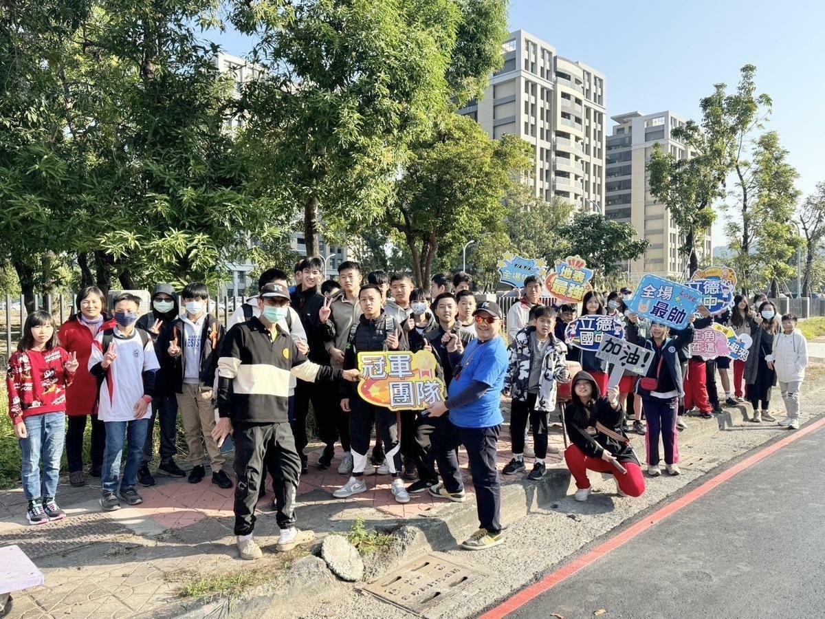 立德國中學生在海功路加油站為今年也首度參加半馬比賽的校長王文正加油打氣。 圖：高雄市教育局提供
