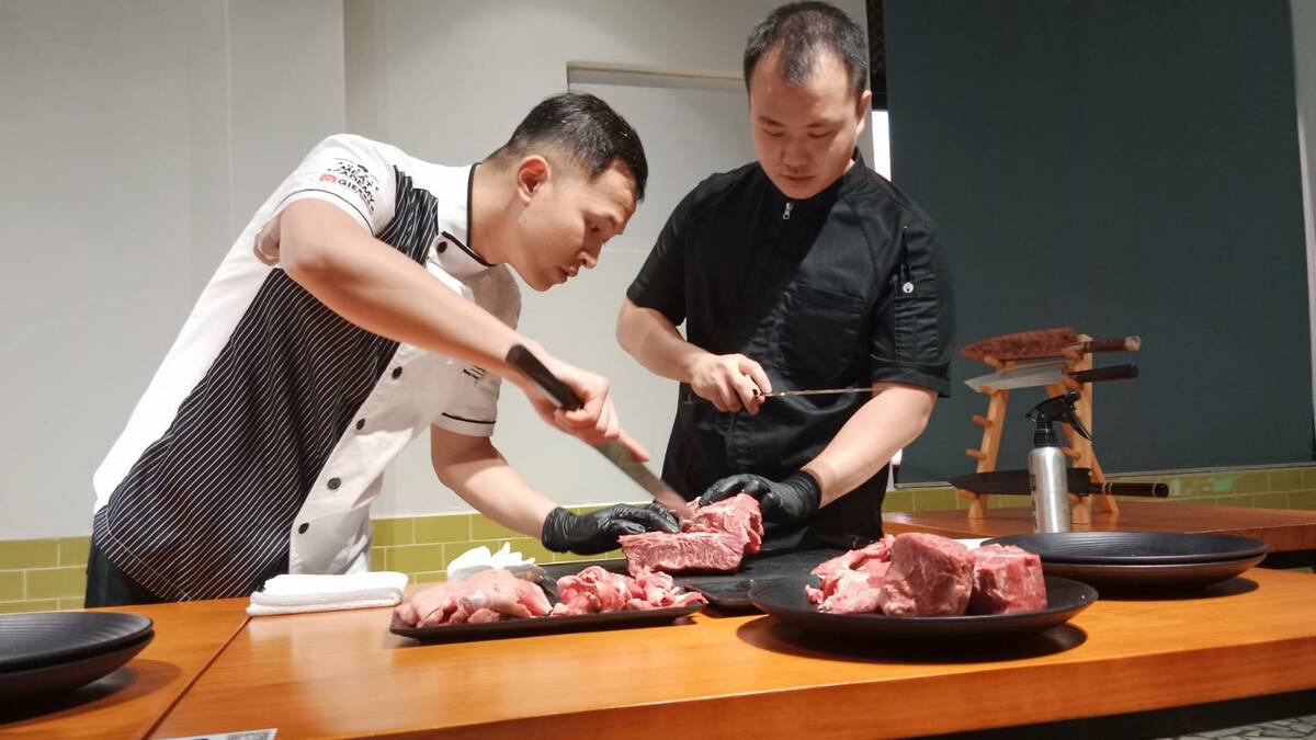 林千畬(右)與廖期弘(左)切磋牛肉修割技術。 圖：孫家銘攝