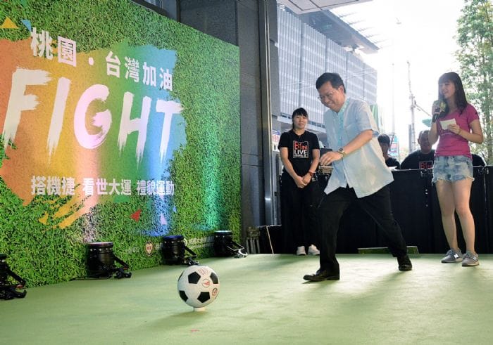 號召大家搭機捷為世大運選手加油，鄭文燦親自上陣試踢足球。 圖：桃園市政府提供
