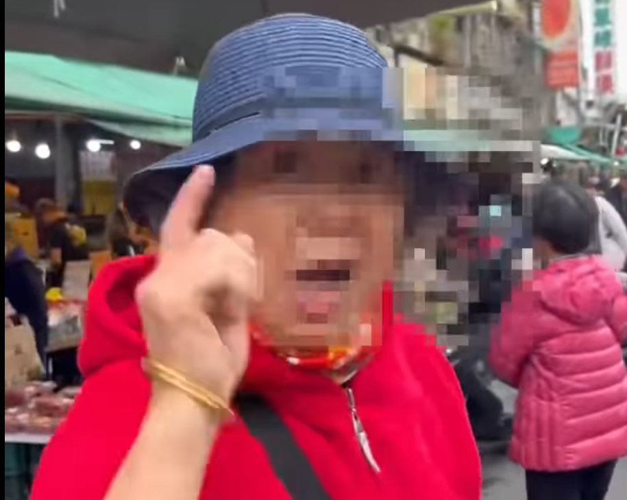 一名身穿紅衣的婦人不僅對志工比出中指，還辱罵、推打，甚至揮拳攻擊。 圖：影片截圖